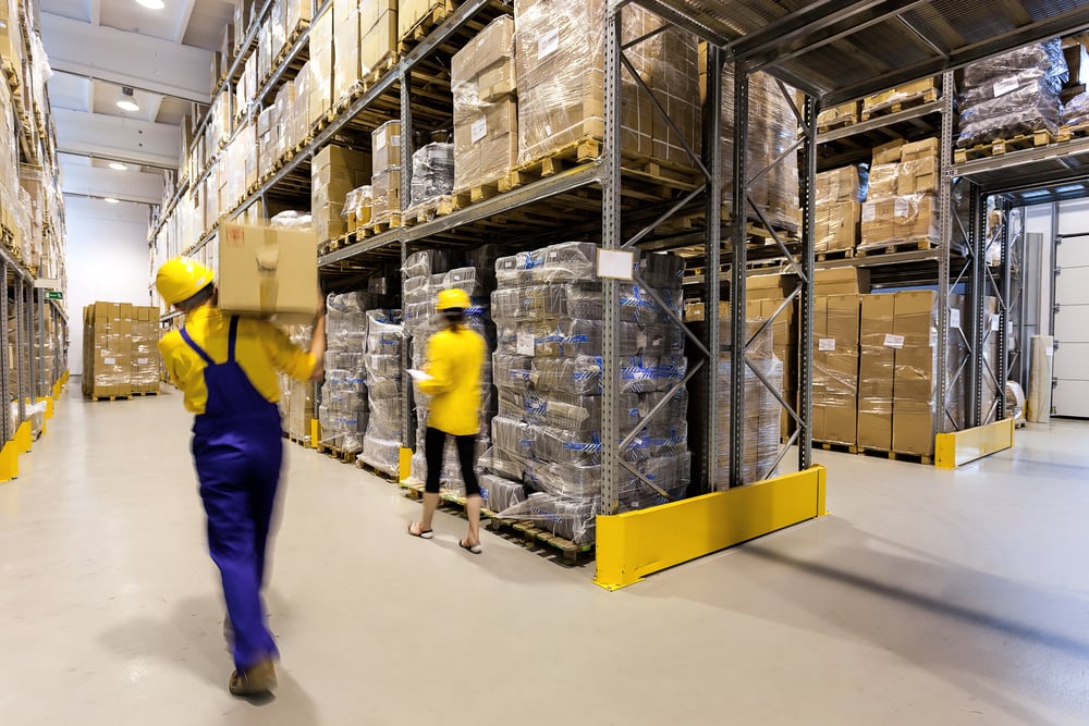 Magazijnmedewerker met doos en manager die producten controleert